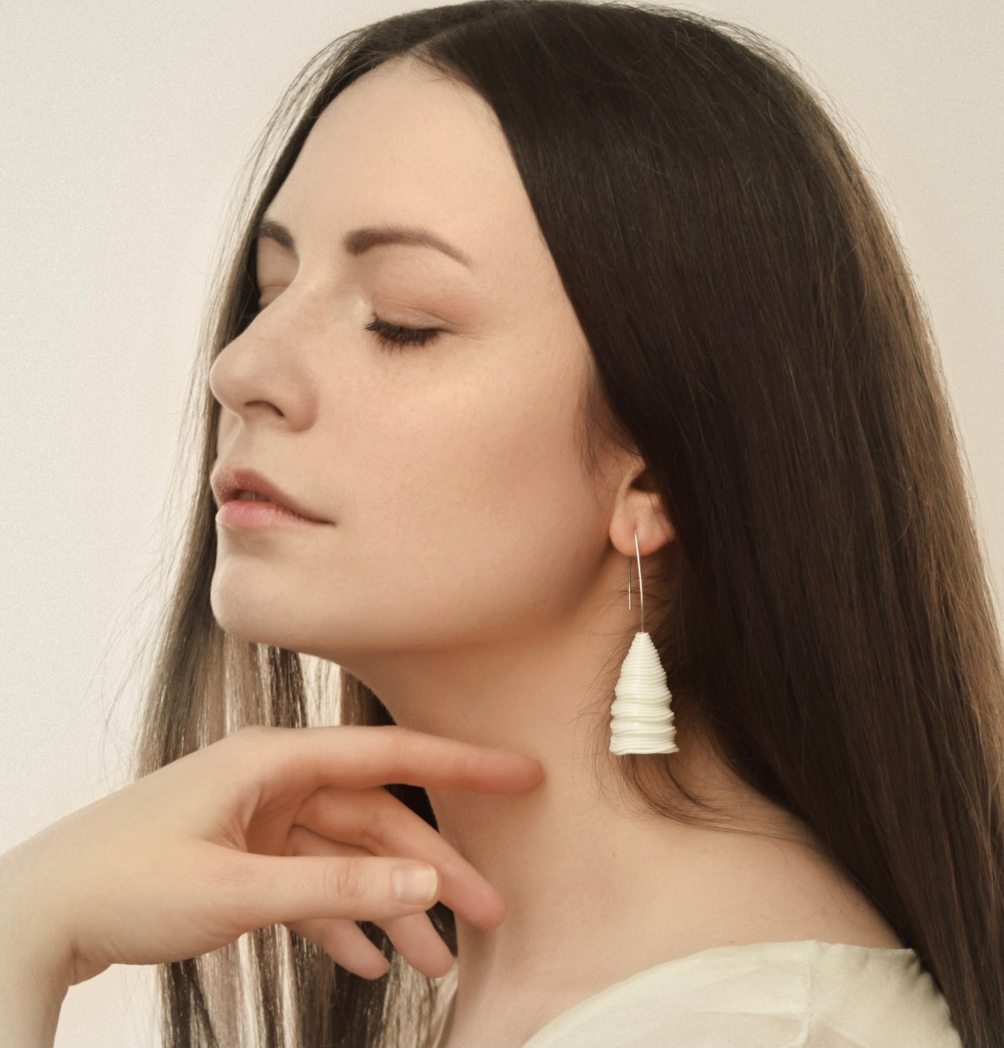 A woman with long dark hair wears the ‘Tornado’ porcelain earring by Serhiy Verbicki, featuring a sculptural, wavy design.