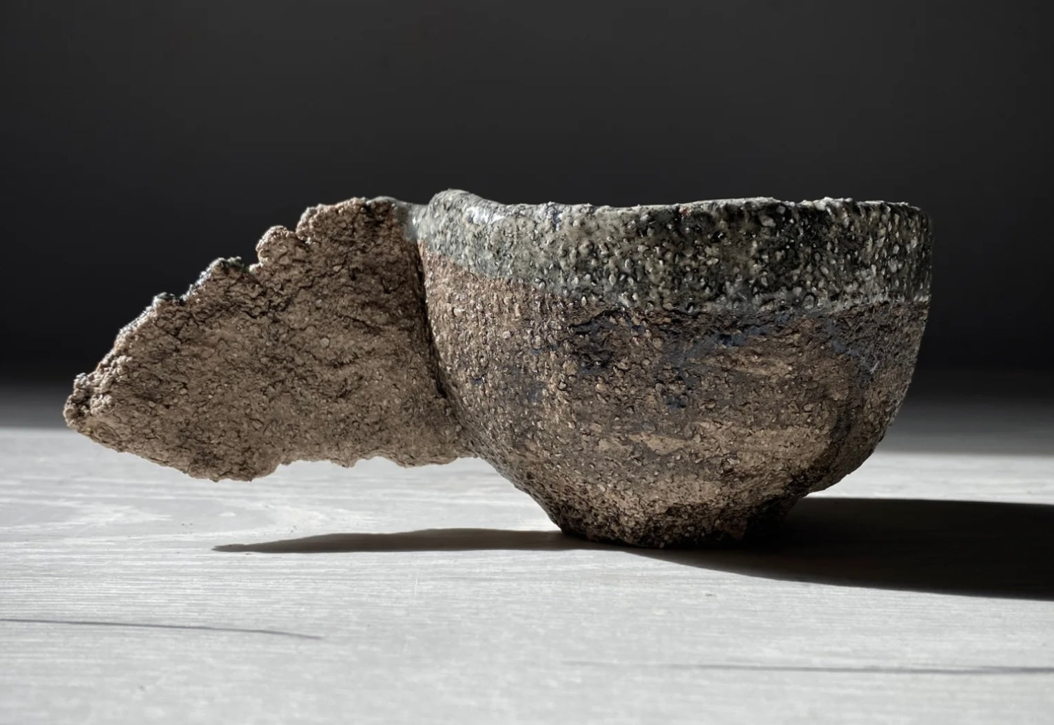 A handcrafted ceramic bowl with a raw, textured surface and an organic protrusion, blending natural imperfection with artistic craftsmanship. This pioneering piece marked the beginning of the 'Primeval Minimalism' style.
