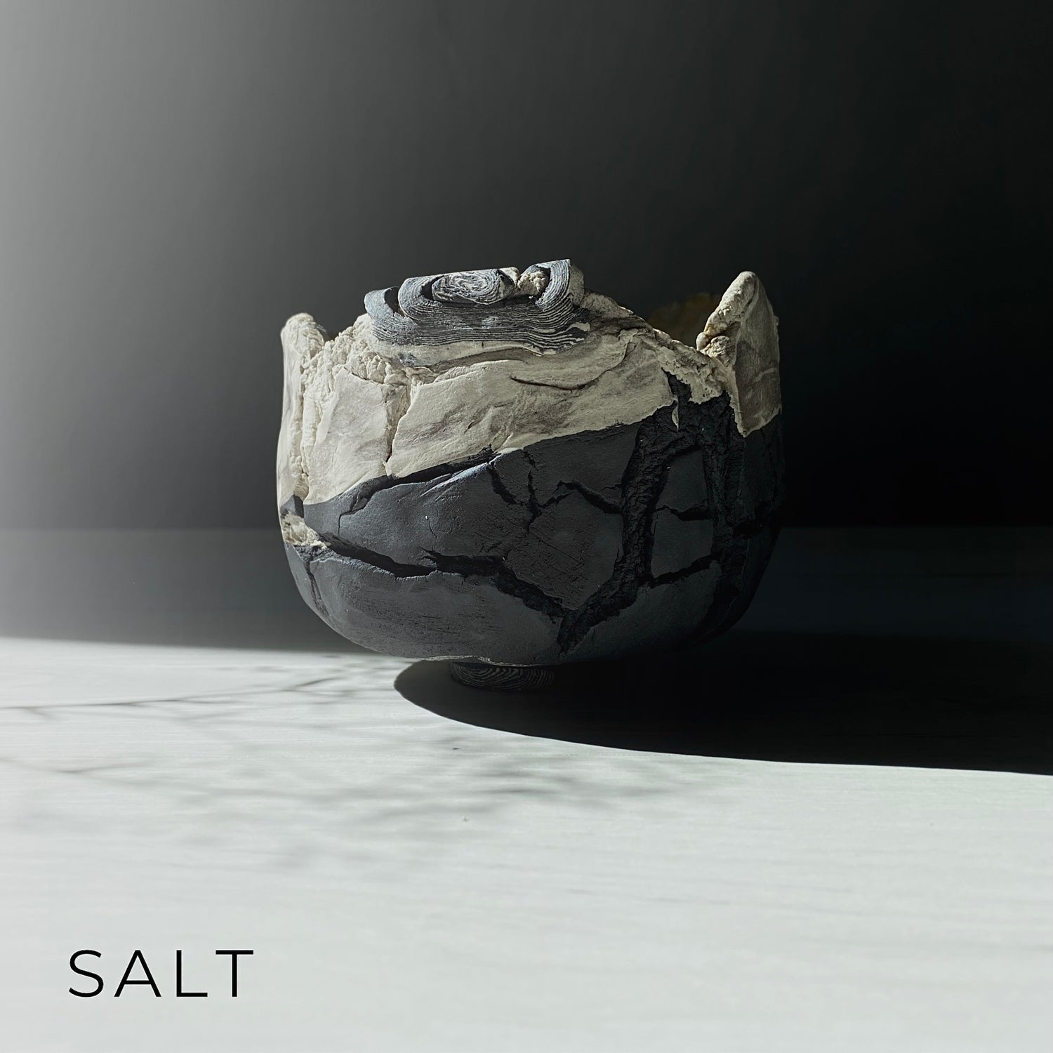 A ceramic bowl from the ‘SALT’ series, featuring layered textures and cracked surfaces, evoking the erosion and transformation of natural elements.