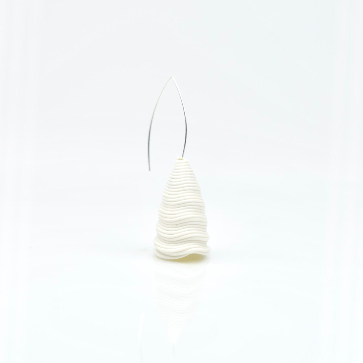 The ‘Tornado’ porcelain earring by Serhiy Verbicki, featuring a sculptural, wavy design with a minimalist silver hook, set against a white background.