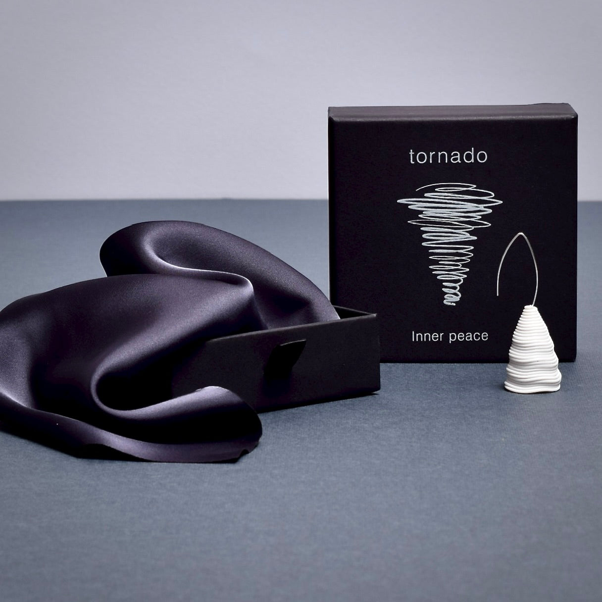 Elegant black packaging for the ‘Tornado’ porcelain earring by Serhiy Verbicki, featuring a minimalist design and a symbolic tornado illustration.